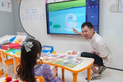 Male teacher showing a math lesson to a kindergartener on the TV