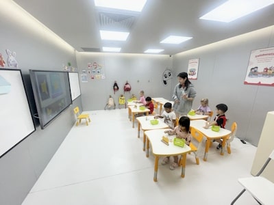 photo of teacher in white classroom, with six 5-7 year old students learning